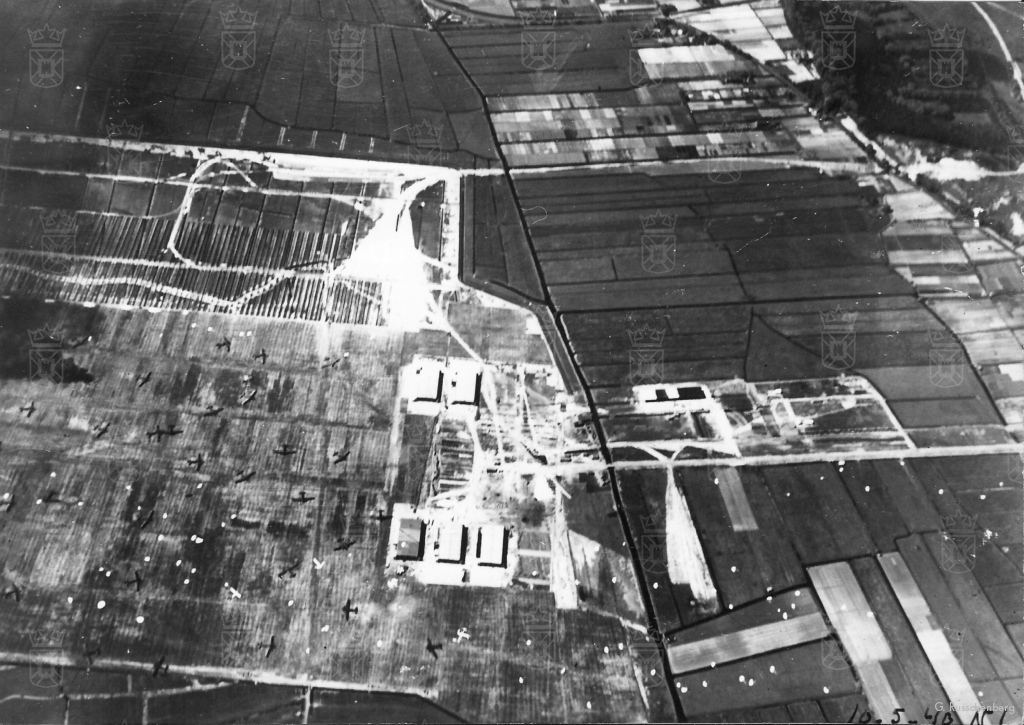 Op deze luchtfoto, gemaakt tijdens de Duitse inval op 10 mei 1940, zijn de drainagesleuven aan de zuidkant van het vliegveld goed te zien. Het vliegveld ligt bezaaid met parachutes en Ju52 transportvliegtuigen.